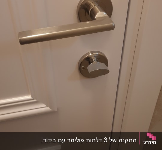 ידית דלת מתכתית על דלת לבנה